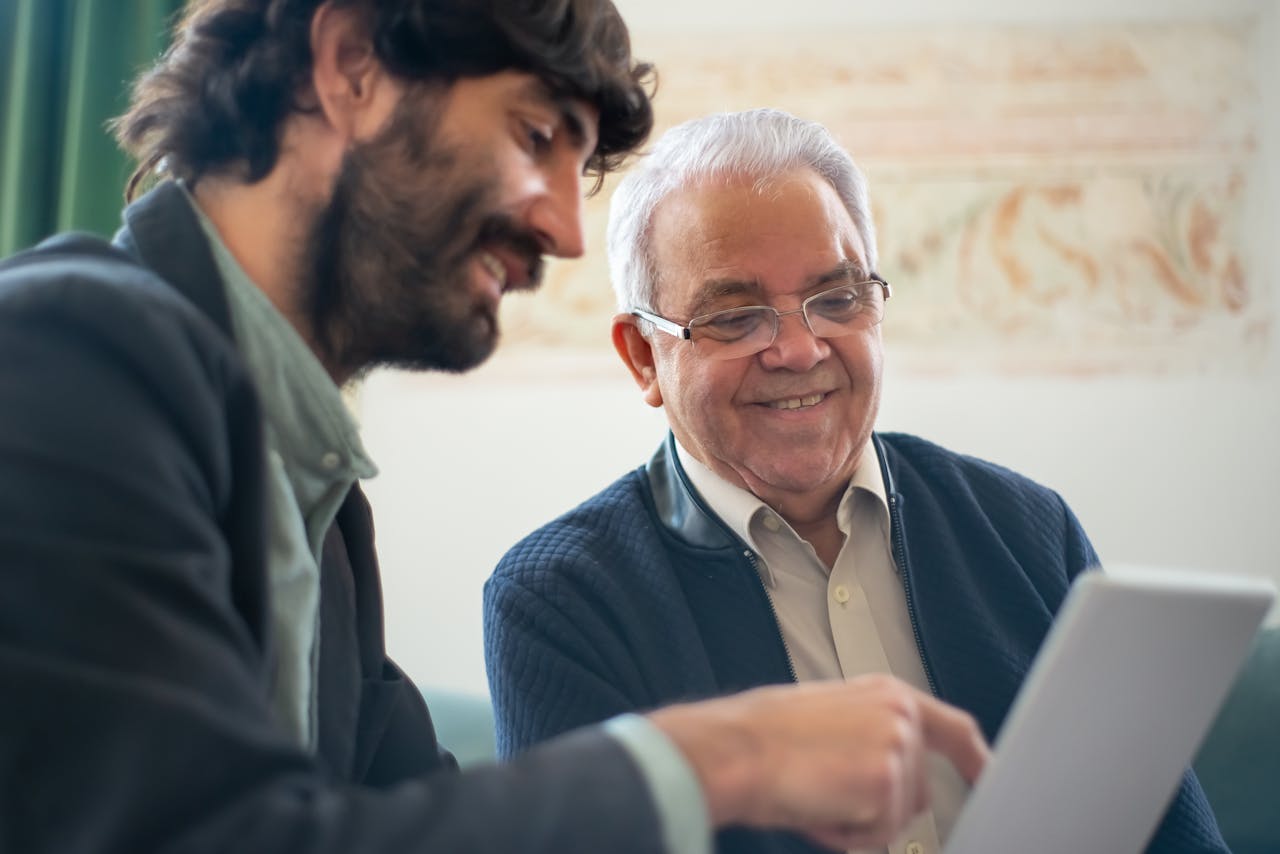Why Insurance Consulting Matters – The Strategic Advantage for Businesses Elderly man discussing business with a younger colleague using a laptop indoors.